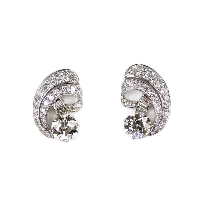 Pair of round brilliant cut diamond and scroll cluster earrings